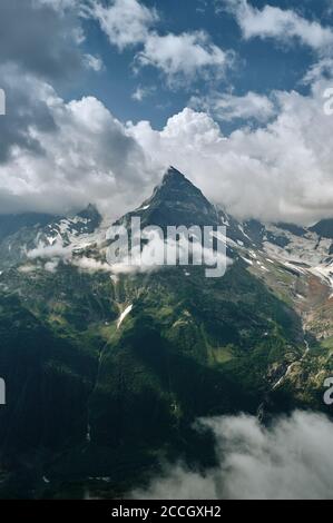 Scharfe Bergspitzen-Landschaft mit bewölktem Himmel, felsigen Bergketten und Gipfeln mit Gletschern und Schneefeldern. Blick auf die wilde Natur. Belalakaya, Dombay, Kaukasus Stockfoto