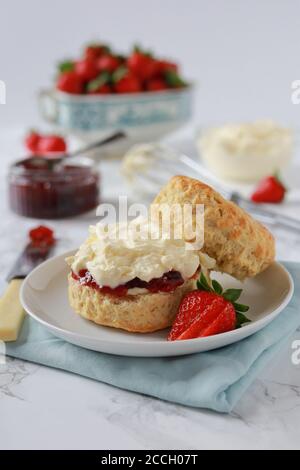 Klassischer englischer Cream Tea. Scone, Sahne und Erdbeermarmelade. Selektiver Fokus auf Scone mit geringer Schärfentiefe Stockfoto