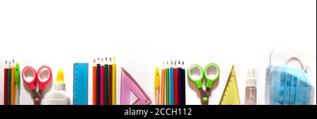 Zurück zur Schule Hintergrundkonzept. Schulmaterial und Mittel zur Prävention von COVID-19 auf weißem Hintergrund. Maske und Desinfektionsmittel. Banner. Copyspace Stockfoto