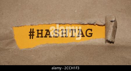 Das Wort Hashtag erscheint hinter zerrissenes Papier Stockfoto