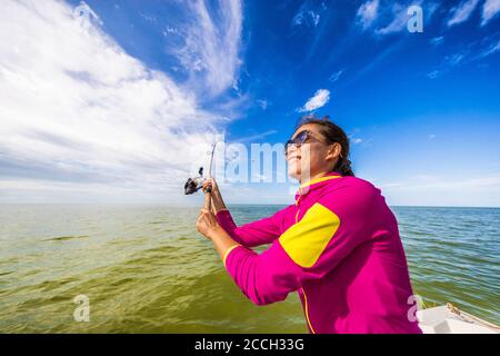 Angeln Frau mit Spaß zu lernen, zu fischen Wurflinie auf dem Ozean. Tourist auf Bootsausflug Stockfoto