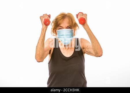 Senior Woman Defiant Über Das Heben Von Zwei Pfund Gewichte Während Des Tragens Eine Gesichtsschutzmaske Stockfoto
