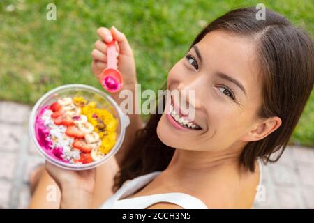 Acai Bowl gesunde Ernährung asiatische Frau zeigt Früchte Smoothie Frühstück draußen im Park zum Mittagessen. Diät vegane Lebensmittel Nahaufnahme. Libellenpüree, Bananen Stockfoto