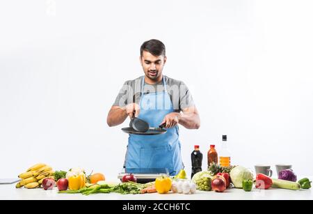 Gutaussehende fröhlich lächelnden indischen Mann Zubereitung von Essen in der Küche, gesundes Essen, Kochkonzept. Stockfoto
