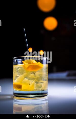 Eleganter, moderner Craft-Cocktail auf den Felsen mit Orangenschalen-Garnitur in angesagter Bar-Atmosphäre Stockfoto