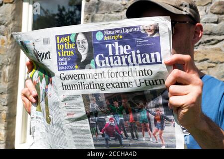 "Regierung gezwungen, zu demütigenden Prüfungen U-Turn" junger Mann Student Lesen Guardian Zeitung Schlagzeile August 2020 London England Großbritannien Stockfoto