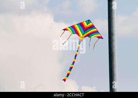 Kinder Lieblings-Spielzeug Drachen an windigen Tagen im Frühjahr, blauen Himmel und weißen Wolken. Ein farbenfroher Drachen schwingt im Wind. Stockfoto