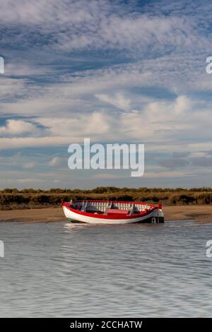 Ein altes offenes Holzboot, das bei Ebbe an der nördlichen norfolkküste in der Nähe von Blakeny an der Küste aufgespült wurde und Brunnen neben dem Meer. Stockfoto