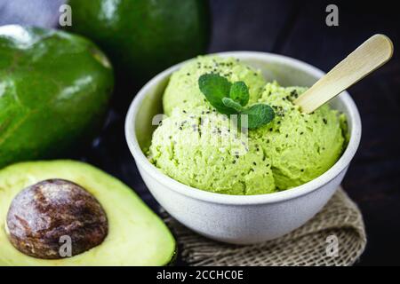 Hausgemachtes Avocado-Eis, hergestellt aus gefrorenen Bio-Früchten ohne Zusatz von Zucker oder Milchprodukten. Veganes Dessert. Dessert in biologisch abbaubarer Plastikschüssel serviert. Stockfoto