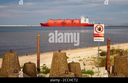 Swinoujscie, Polen - 21. August 2020: Kein Eintrittsschild in geschlossener Schutzzone beim LNG-Terminal in Swinoujscie mit Tankwagen in der Ferne bei Sonnenuntergang. Stockfoto