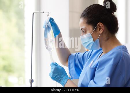 Krankenschwester in Maske und in Schutzhandschuhen Vorbereitung Dropper für Patient im Krankenhaus Stockfoto