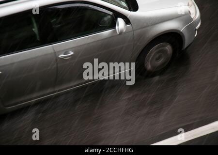 Verschwommenes Auto auf der Straße vom starken Regen mit Hagel getroffen, an einem regnerischen Tag in Bewegung verschwommen Schwenken von oben geschossen Stockfoto