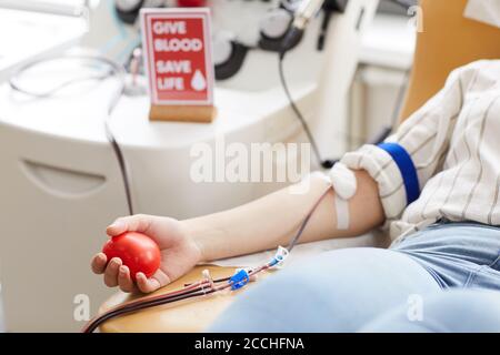 Nahaufnahme der Spenderin mit Ball in der Hand und In Katheter in ihrem Arm Blut spenden im Krankenhaus Stockfoto
