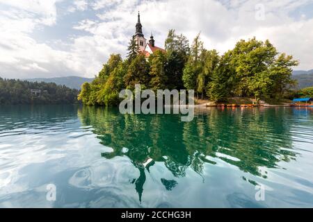 Die kleine Insel in der Mitte des slowenischen Sees von Bled, umgeben von Vegetation, reflektiert auf dem Wasser Stockfoto