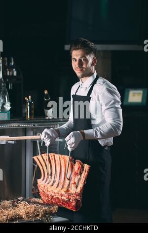 Der Kellner oder Koch bekommt trockenes Fleisch im Kühlschrank. Stockfoto