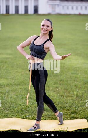 Schöne junge Frau, während das Tragen eines engen Sport-Outfit, misst ihre Taille nach Pilates oder Yoga-Übungen Stockfoto