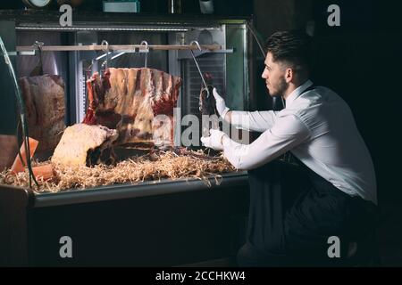 Der Kellner oder Koch bekommt trockenes Fleisch im Kühlschrank. Stockfoto