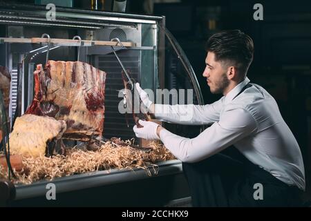 Der Kellner oder Koch bekommt trockenes Fleisch im Kühlschrank. Stockfoto