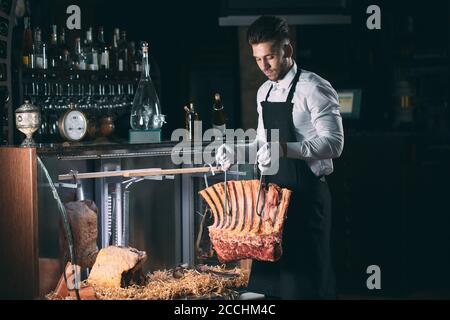 Der Kellner oder Koch bekommt trockenes Fleisch im Kühlschrank. Stockfoto