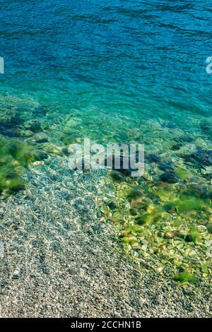 Blaues Meerwasser mit Steinen im Moos. Stockfoto