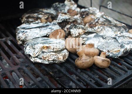 Pilz und Fleisch in der Folie auf dem Grill. Wochenende und Picknick Stockfoto