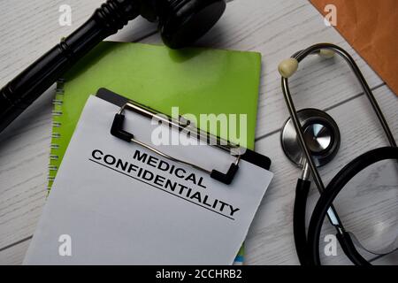 Text zur medizinischen Vertraulichkeit schreiben auf einen Papierkram und gavel mit Stethoskop isoliert auf Schreibtisch. Stockfoto