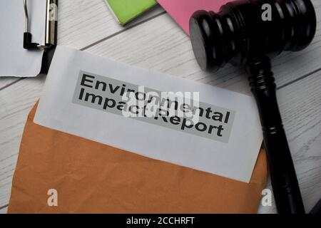 Text des Umweltverträglichkeitsberichts mit braunem Dokumentumschlag und Gavel auf dem Schreibtisch isoliert. Stockfoto