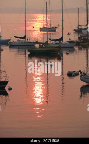 Sonnenaufgang über dem Hafen, Monterey Bay, CA. Waldbrände haben den Himmel und das Wasser rosa gemacht und wunderschöne Reflexionen im Wasser geschaffen. Stockfoto