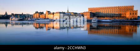 Boote verankert entlang Skeppsbron bei Sonnenaufgang mit Königspalast und Old Town in Stockholm Stockfoto