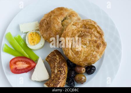 Traditionelles türkisches Bohnenkraut 'Boyoz' auf Teller mit Sesambagel, Ei, Oliven Und Tomatenscheiben, Frühstücksteller in Weiß mit Tee Stockfoto