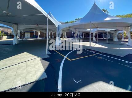 Schulen bereiten sich auf das persönliche Lernen vor, indem sie während der Coronavirus-Pandemie Zelte auf der Blacktop für Klassenräume im Freien errichten. Stockfoto