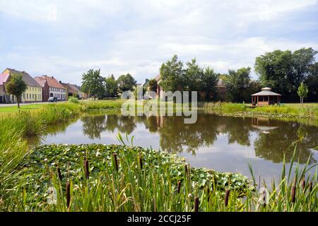 18. August 2020, Brandenburg, Niedergörsdorf/ OT Oehna: Häuser und ein Teich in der Nähe des Dorfzentrums. Auf der rechten Seite ist ein Unterstand mit Mandala Dachkonstruktion. Das Dorf am Rande der Fläming wurde erstmals 1161 in einem Brief eines Bischofs erwähnt. Das Dorf liegt in der Nähe der Stadt Jüterbog an der Fläming-Skate und ist auch ein beliebtes Ausflugsziel wegen seiner Freibad und Campingplatz. Foto: Soeren Sache/dpa-Zentralbild/ZB Stockfoto