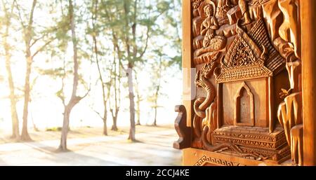 Offenes Fenster des buddhistischen Tempels mit Sonnenuntergang Strand verschwommen im Hintergrund, Muster des buddhistischen Tempels geschnitzten Holzfenster. Wat Khuan, Thailand. Stockfoto
