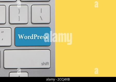 WORDPRESS-Text auf der Tastatur über gelbem Hintergrund. Geschäfts- und Technologiekonzept Stockfoto