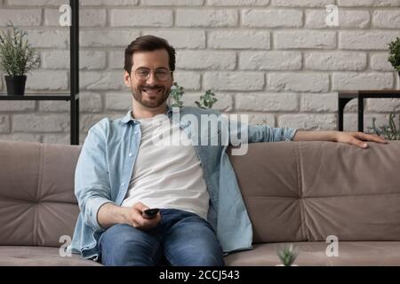 Glücklicher Kaukasischer Mann schaut Fernsehen und entspannt im Wohnzimmer Stockfoto