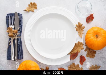 Herbstsaison Tischeinstellung mit Kürbissen, Blättern und Besteck - Gabel und Messer. Weißer leerer Teller und Dekoration um. Speicherplatz kopieren. Overhead-Aufnahme. Stockfoto