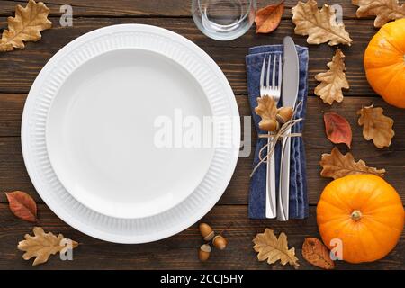 Herbstsaison Tischeinstellung mit Kürbissen, Blättern und Besteck - Gabel und Messer. Weißer leerer Teller und Dekoration um. Speicherplatz kopieren. Overhead-Aufnahme. Stockfoto