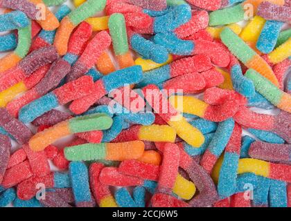 Draufsicht flache Lage von zuckerbeschichteten Gummiwürmern. Halbfarbig rot und blau, rot und gelb, grün und orange. Stockfoto