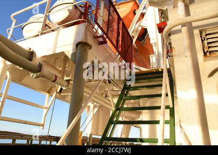 Grüne Treppe mit rotem Schutz Metall Sicherheitsgrill auf der Oberseite gegen Piraterie Angriff auf Containerschiff. Schritte, die zum Emergency Embarkation Deck führen. Stockfoto