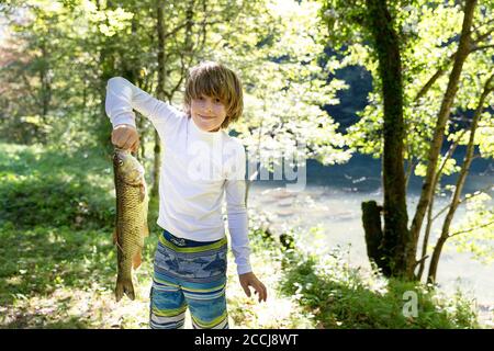 Stolzer Junge mit Fisch im Fluss gefangen Stockfoto