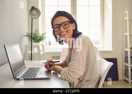 Arbeiten von zu Hause aus. Geschäftsfrau, die von zu Hause aus an einer Online-Konferenz teilnimmt. Glücklicher Freiberufler mit Laptop Stockfoto