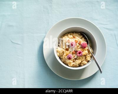 Quinoa porige auf der Tischplatte. Schüssel mit Quinoa-Milchbrei mit Beeren und Mandel über blauer Leinentischdecke. Speicherplatz kopieren Stockfoto
