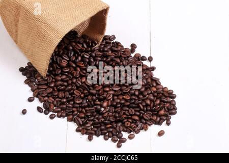Häkelbeutel Kaffeebohne Verpackung und eine Sammlung von Geröstete Kaffeebohnen auf einer weiß lackierten Holzbasis Stockfoto