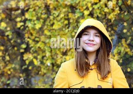 Teenager-Mädchen in einem gelben Kapuzenmantel Porträt Herbst Saison Stockfoto