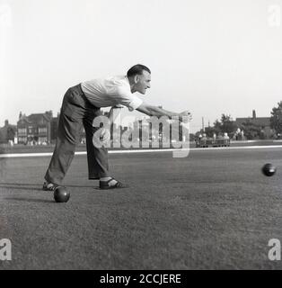 1950er Jahre, historisch, in einem offenen Bereich, draußen auf einem Rasen, ein Gentleman Biegen über Rollen einen schweren Ball, spielen eine Sportart bekannt als Schüsseln oder Rasenschalen, gespielt auf flach eng geschnittenem Gras, eine glatte Oberfläche als grün bekannt, England, Großbritannien. Stockfoto