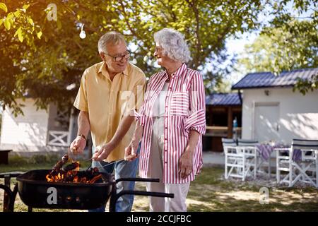 Glückliche ältere Familie bereitet Grill im Garten zusammen. Stockfoto