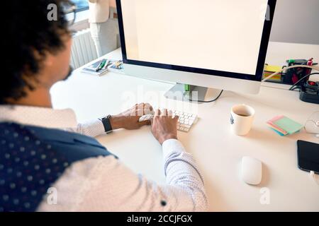 Junger Geschäftsmann, der im Büro am Computer arbeitet Stockfoto