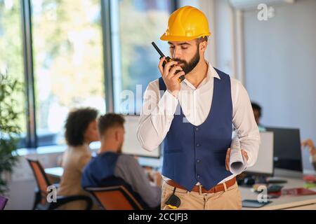 Junger Architekt mit Walkie Talkie aus dem Büro Stockfoto