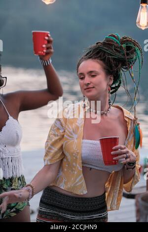 Junge Frau trinkt Bier und tanzt mit ihren Freunden Feiern Sie im Freien Stockfoto