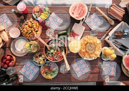 Hochwinkelansicht des Feiertagtisches mit Gemüsesalatobst Und verschiedene Snacks im Freien Stockfoto